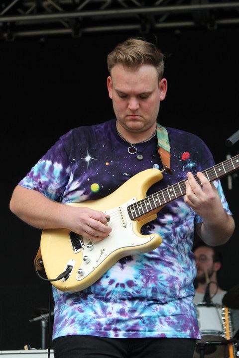 Guitarist playing a white electric guitar outdoors