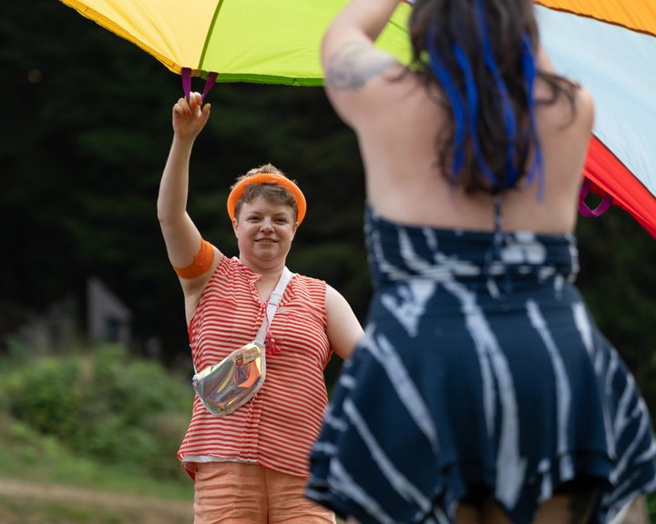 Festival attendees dancing beneath a colorful fabric canopy