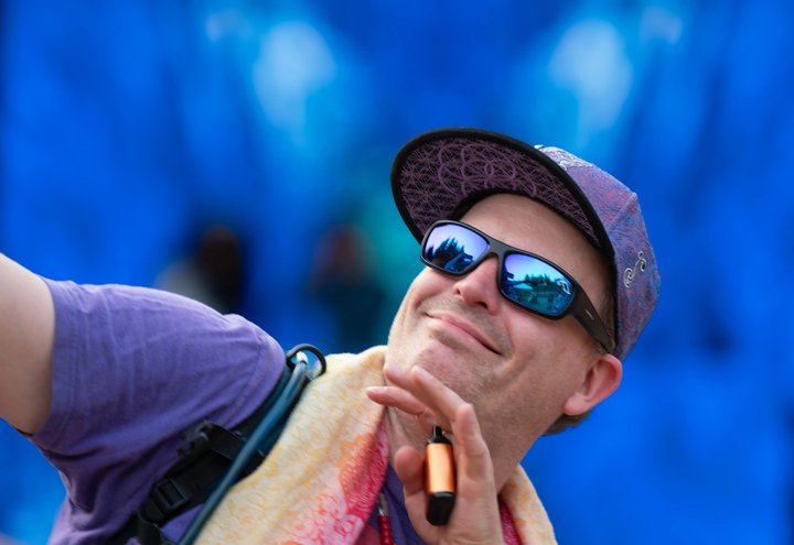 Festival attendee smiling in sunglasses and a cap