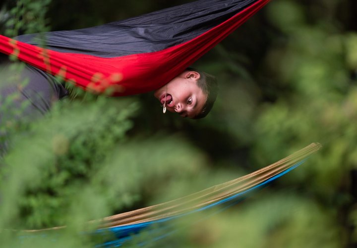 Festival attendee relaxing in a red hammock among the trees