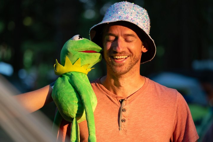 Festival attendee holding a green frog puppet